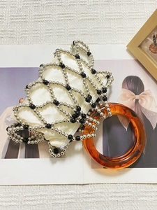 Close-up of beaded handbag with amber resin handle and white satin inner pouch