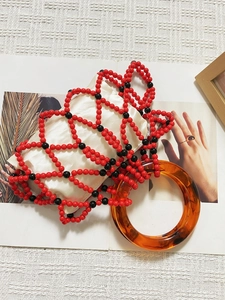 Detail of beaded bag with red and black lattice, ivory pouch and amber resin handle