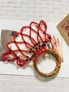 Detail of red and black beaded mesh handbag featuring natural bamboo round handles