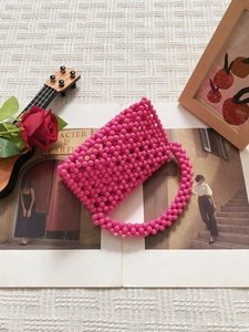 Fashionable pink acrylic beaded handbag with round top handles and woven triangle texture