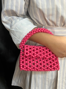 Detail of rose pink handmade beaded handbag with high-gloss resin beads and woven texture