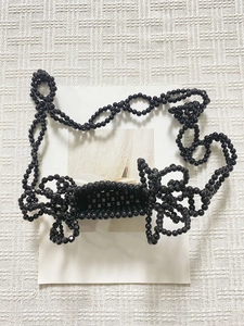 Dettaglio della mini borsa nera fatta a mano in perline con decorazione a fiocco