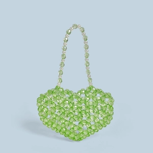 Détail d'un sac à main fait main en forme de cœur avec perles vertes et perles blanches