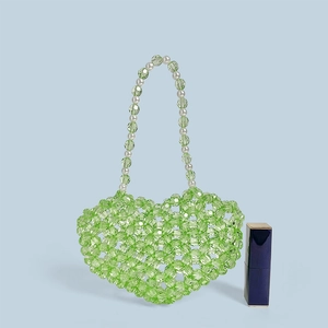 Vue détaillée d'un mini sac perlé vert en forme de cœur avec perles et un rouge à lèvres