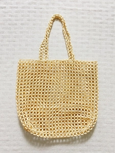 Détail d'un sac à main beige tressé avec perles au style bohème pour la plage