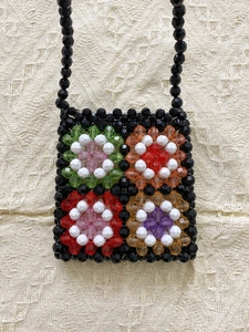 Handmade beaded mini crossbody bag with colorful floral patterns on a black bead base