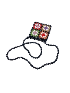 Detailed macro view of handmade black beaded mini bag featuring colorful flower patterns