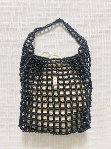 Handmade black beaded tote bag with a cream drawstring liner on a white knit background