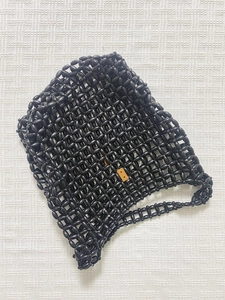 Detail of handcrafted black beaded tote with glossy woven beads and a small brown tag