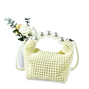 Detail of handmade pearl woven handbag featuring large pearl handle and crossbody chain