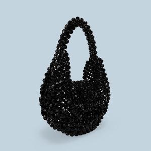 Detailed macro view of black faceted acrylic beads and handmade woven texture on handbag