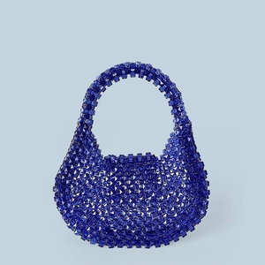 Macro shot of geometric faceted dark blue acrylic beads on a handmade luxury handbag