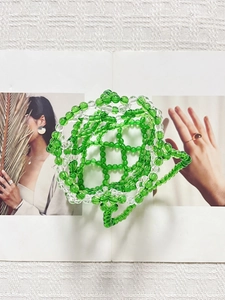 Close-up of handmade green and clear acrylic beaded handbag with woven hollow design