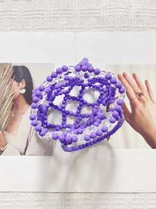 Macro shot of purple and clear acrylic beads in a hexagonal hand-woven pattern