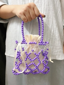 Detailed close-up of handmade purple beaded handbag with cream satin drawstring lining