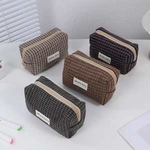 Set of four plaid checkered makeup pouches in various colors on a tidy white desk