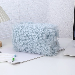 Close-up of light blue plush pencil case with zipper closure on a white desk setup