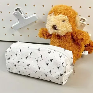 White canvas stationery pouch with black bow prints and silver zipper closure