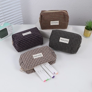 Detail of four colorful houndstooth plaid storage pouches with zippers and woven labels
