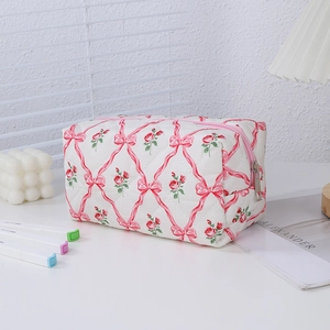 Detail of quilted makeup bag with rose and bow print featuring a pink zipper closure