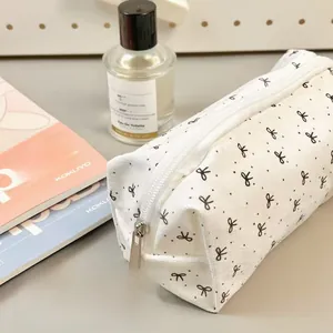 Detail of white canvas pencil case with black bow patterns and silver metal zipper
