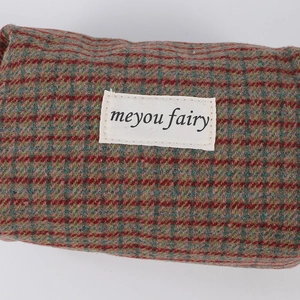 Detailed close-up of retro plaid fabric and woven brand label on a makeup bag