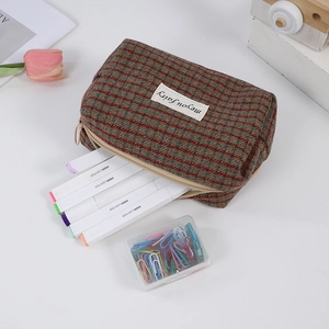 Detail of red and green plaid storage bag featuring a zipper and woven logo label