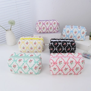Floral quilted stationery pouches with ribbon bows in six pastel colors on white desk