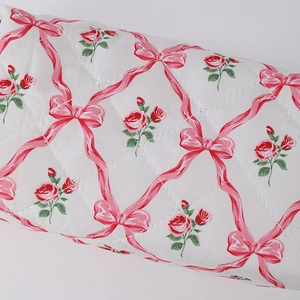 Close-up of quilted floral pencil case with pink ribbons and rose patterns