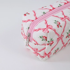 Close-up of quilted floral pencil case featuring pink bow and red rose pattern print