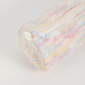 Gros plan d'une trousse en tweed pastel avec texture douce et détail de fermeture éclair