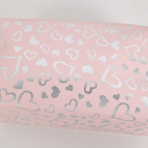 Close-up of pink makeup bag texture with silver heart patterns and fine material detail