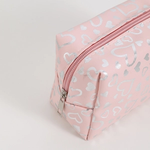 Detail shot of pink heart-patterned makeup bag showing the metal zipper and PU leather texture