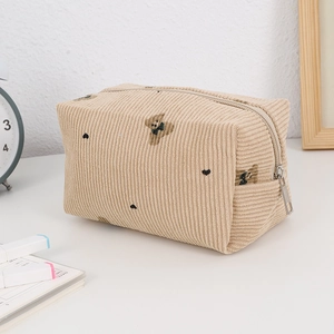 Detailed texture of corduroy makeup bag featuring embroidered bear and heart patterns