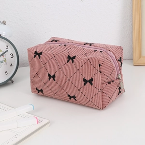 Detailed close-up of pink corduroy makeup bag with black bow patterns and silver zipper