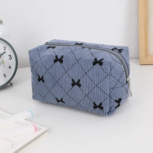 Detail of blue corduroy makeup bag with bow embroidery and quilted rhombus pattern