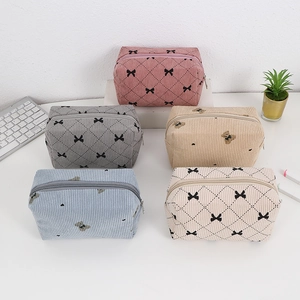 Corduroy makeup bags in five colors with bow and bear patterns on a clean white desk