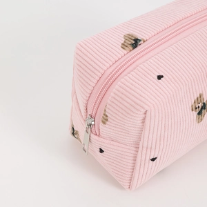 Detail of pink corduroy makeup bag featuring embroidered bears and metal zipper