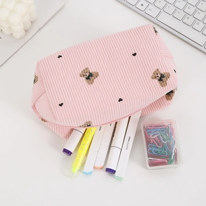 Pink corduroy makeup bag with bear print and zipper shown on a minimalist white desk