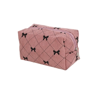 Pink corduroy makeup bag with quilted bow design and top zipper closure