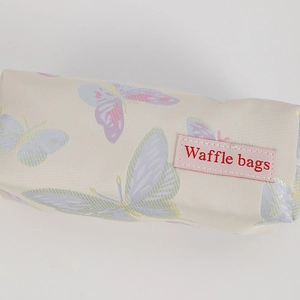 Detailed macro view of butterfly printed pencil case with embossed leather brand label