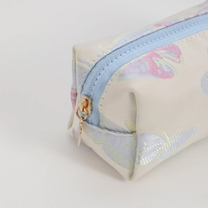 Detailed close-up of blue zipper with gold metal ring pull on butterfly pencil case
