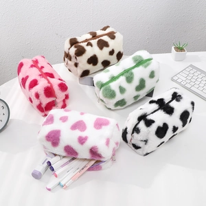 Detailed view of plush heart pattern pouches in five colors on a white office desk