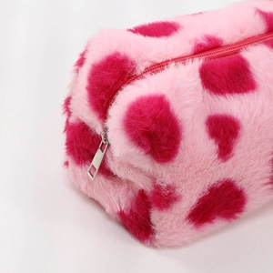 Detail of pink cow print plush cosmetic bag showing soft fur texture and silver metal zipper