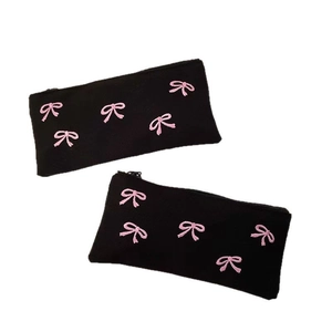 Two black canvas stationery bags with pink bow embroidery and zipper closure