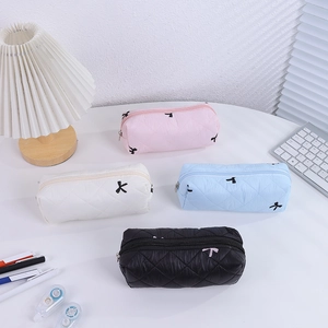 Quilted fabric bow pencil cases in four colors on desk with school stationery