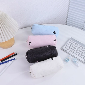 Quilted bow pencil cases in four colors shown with desk accessories in a top-down view