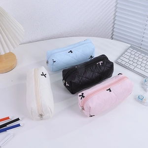 Quilted bow pencil cases in multiple colors shown on a desk with stationery items