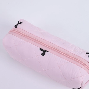 Close-up of pink quilted stationery bag with black X embroidery and zipper detail