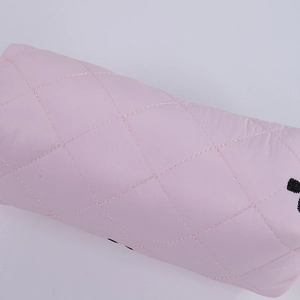 Detailed macro view of pink quilted fabric pencil case with black embroidered accents